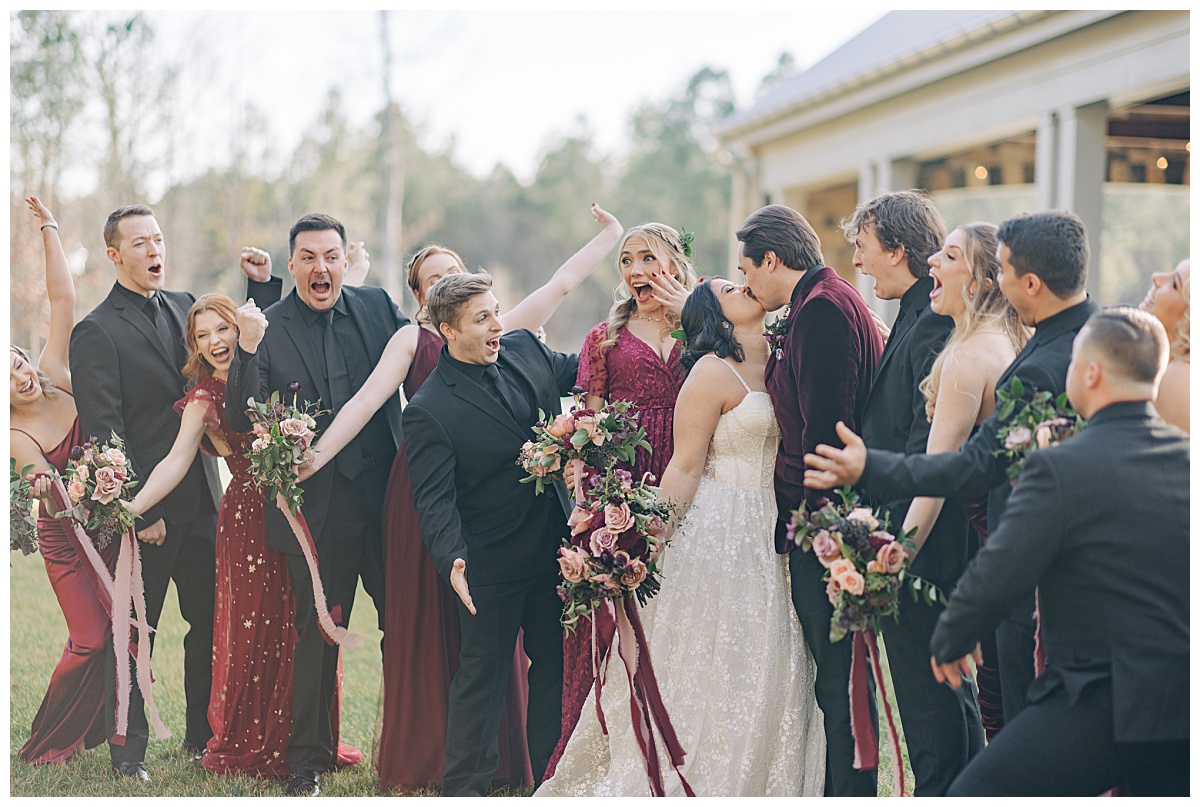 Wedding party cheering on bride and groom as they kiss by Virginia Wedding Company