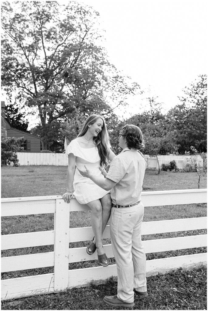 woman sitting on fence smiling down at man